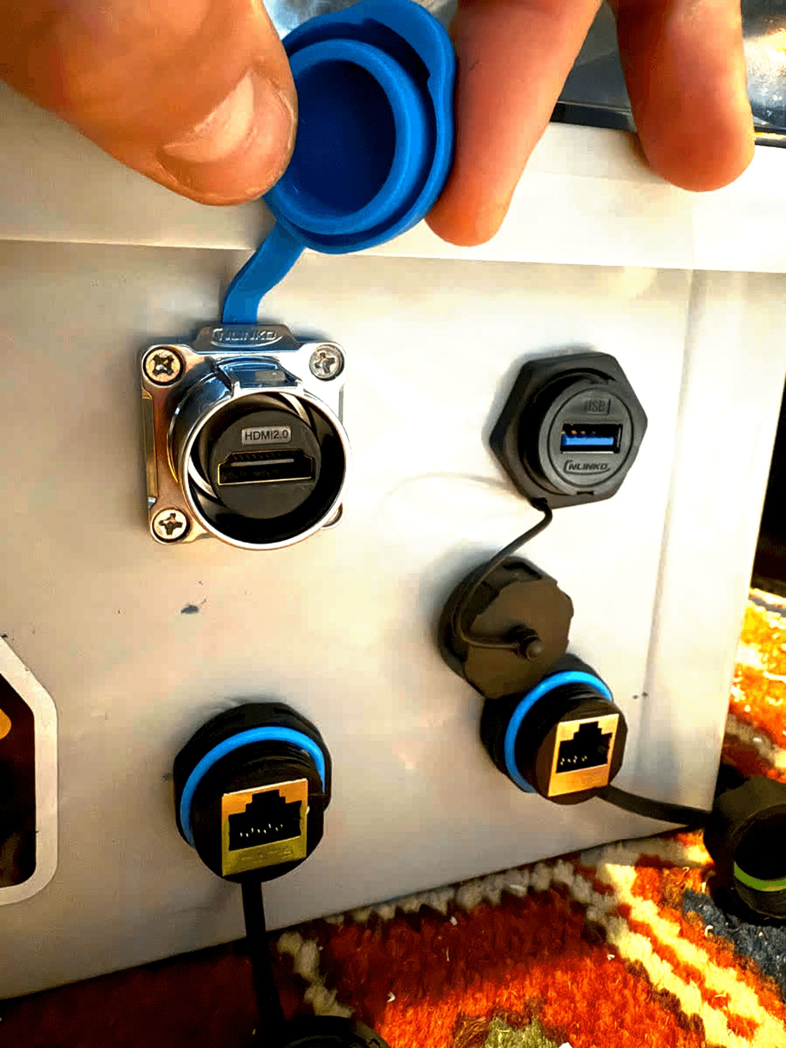Sealed HDMI, USB and Ethernet ports on the side of the box, one cap held open.